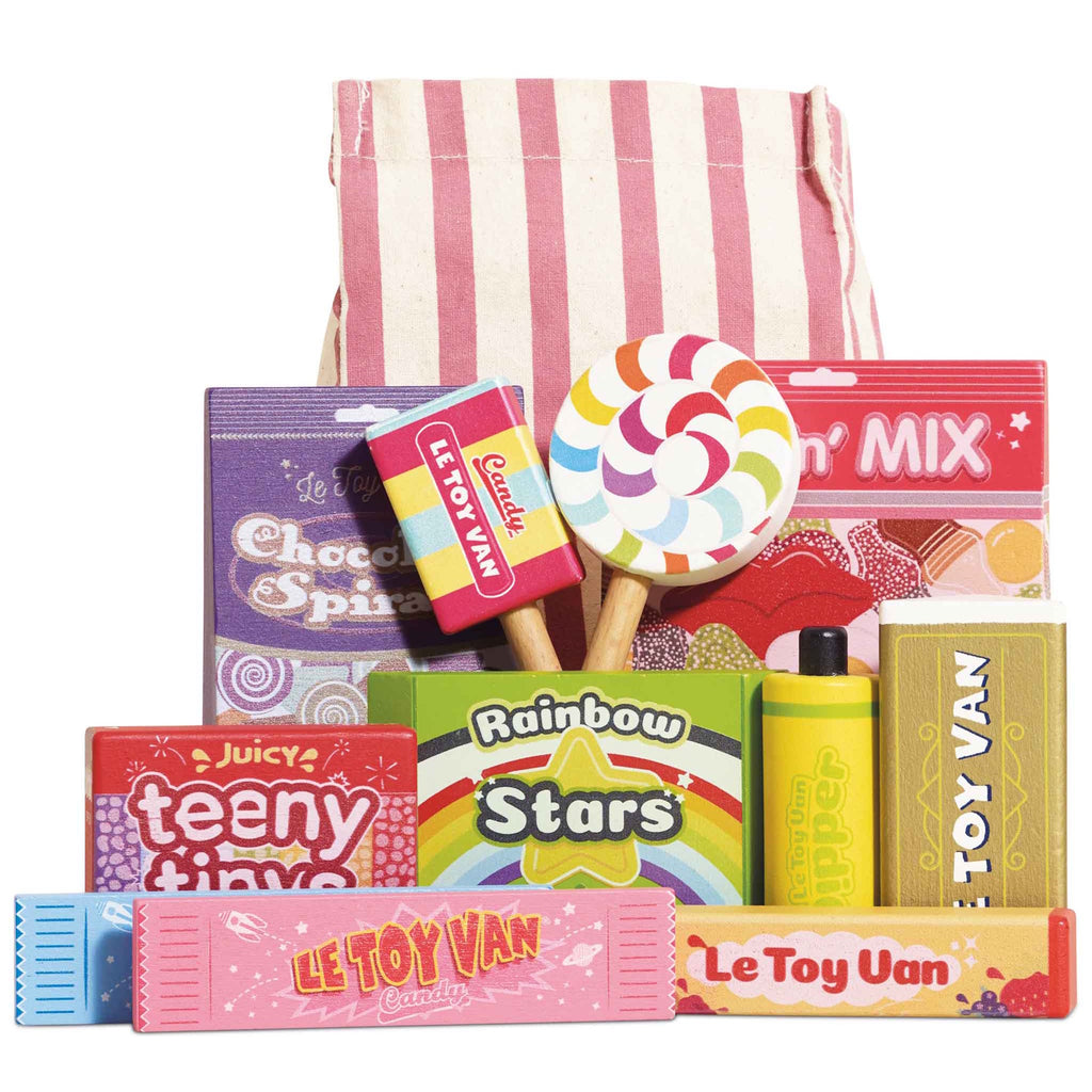 A vibrant assortment of colorful toy candies with labels like "Le Toy Van" and "Rainbow Stars," displayed in front of a red and white striped bag. Playful and cheerful atmosphere.