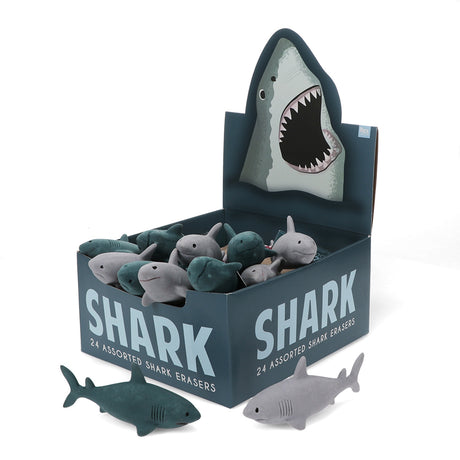 A display box of 24 shark-shaped erasers with various shades of gray and teal. The box features a shark illustration, conveying a playful theme.