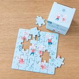 Cute puzzle on wooden table, featuring mice in red outfits dancing with musical notes. A box in the corner shows the same animated design. Playful mood.