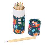 A colorful cylindrical box with vibrant floral and fairy patterns holds sharpened colored pencils. One pencil lies outside, creating a playful and creative vibe.