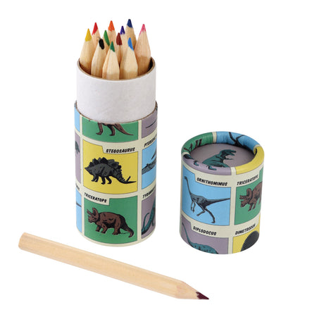 A cylindrical container with colorful dinosaur illustrations holds sharpened colored pencils. The matching lid is beside it, and a single pencil lies in front.