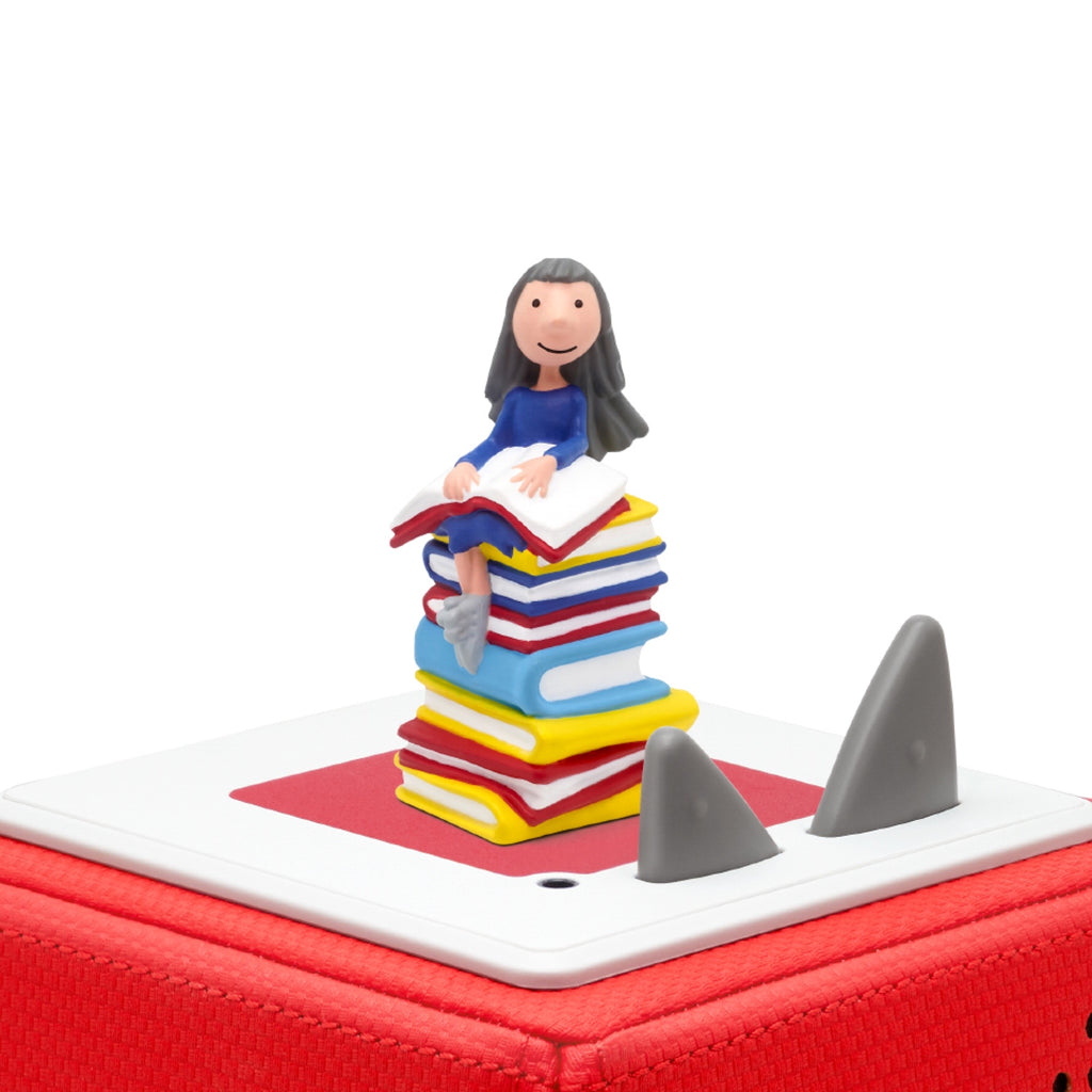 A whimsical figurine sits atop a colorful stack of books, evoking a playful reading theme.