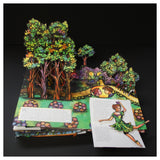 Pop-up book depicting a vibrant fairy-tale scene with colorful trees, a stone archway, and a small path. A fairy figure appears animated and whimsical.