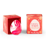 Pink and white marbled Moulin Roty bouncing dragon egg toy next to its red display box.