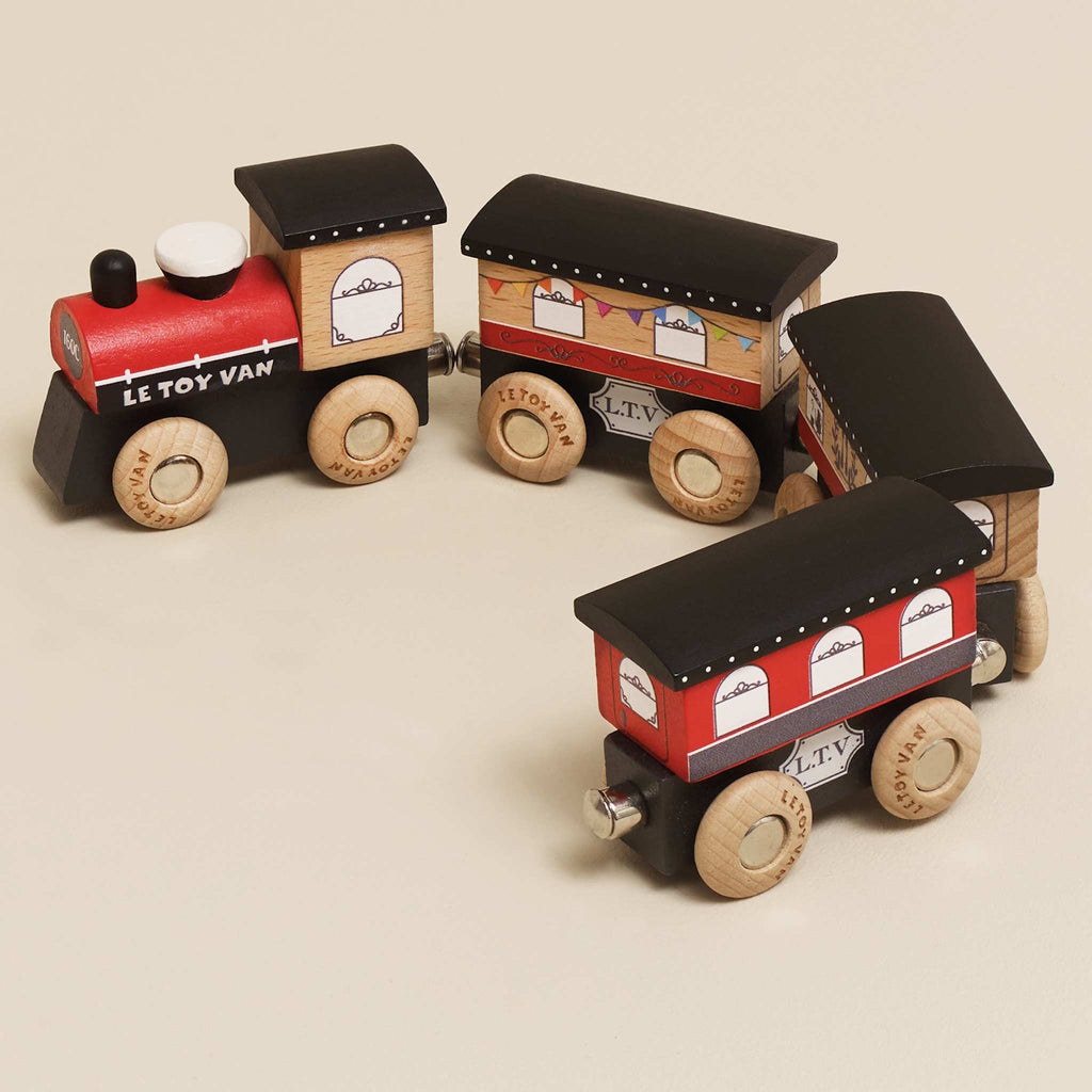 Wooden toy train with a red engine and three brown cars. Each car has detailed window decals and wooden wheels, evoking a playful, vintage charm.