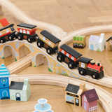 Wooden toy train on a track with arched bridges, surrounded by colorful miniature houses and shops on a wooden floor; playful and whimsical scene.