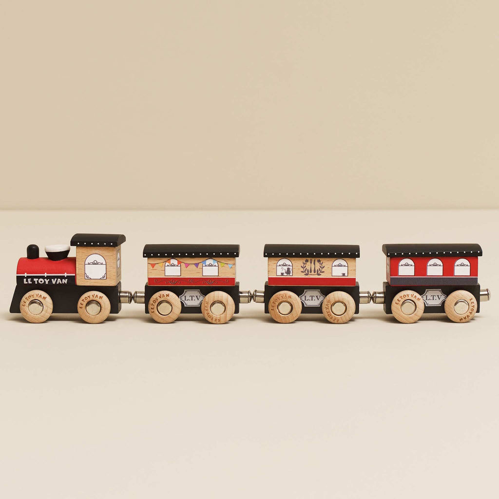 Wooden toy train with a red engine and three brown cars. Each car has detailed window decals and wooden wheels, evoking a playful, vintage charm.