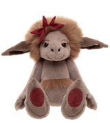 Front-facing plush creature with grey fur, big floppy ears, fluffy brown mane, burgundy bow, and red paw pads.