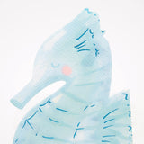 Light blue, seahorse-shaped paper napkin with watercolor texture and dark blue details on a white background.