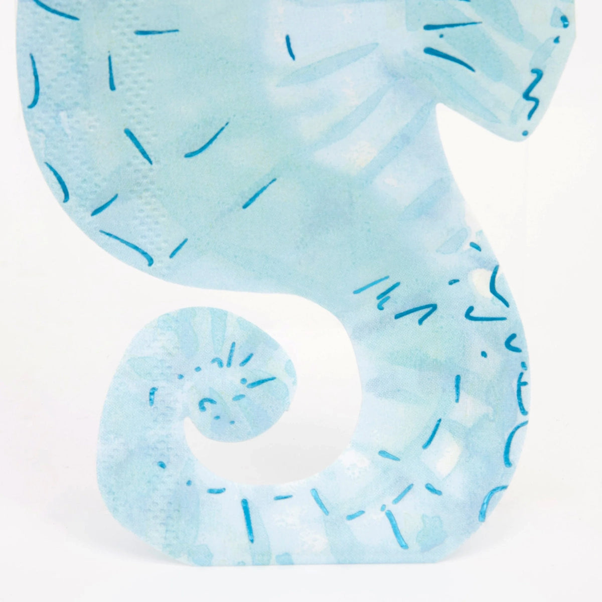 Close-up of a blue watercolor seahorse-shaped paper napkin with dark blue dashes.