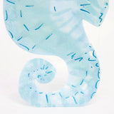 Close-up of a blue watercolor seahorse-shaped paper napkin with dark blue dashes.