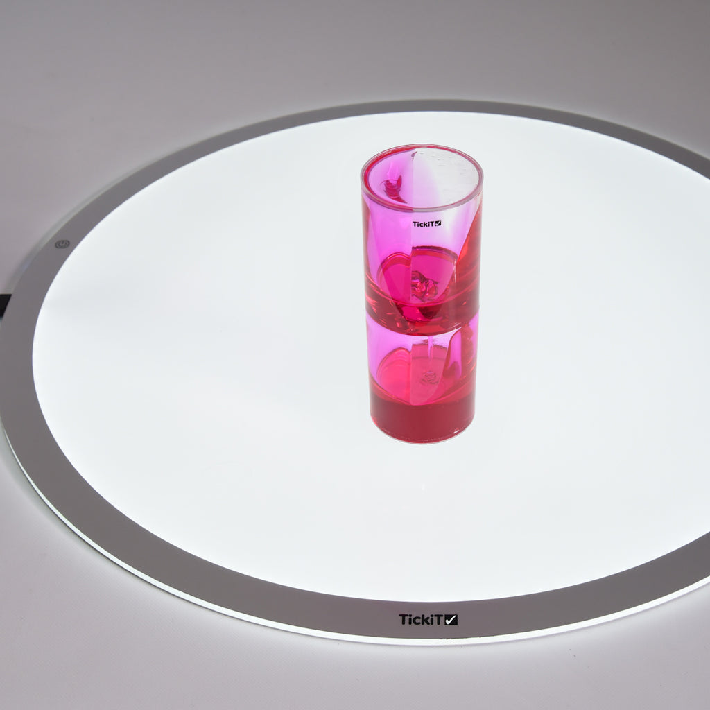 Pink liquid motion timer with bubbles inside a transparent cylindrical container, placed on a white surface, creating a calming, playful vibe.