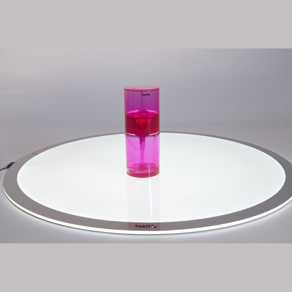 Pink liquid motion timer with bubbles inside a transparent cylindrical container, placed on a white surface, creating a calming, playful vibe.
