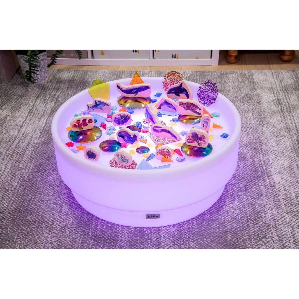 A softly glowing LED table with a shallow well, designed for sensory exploration, water play, and immersive learning experiences.