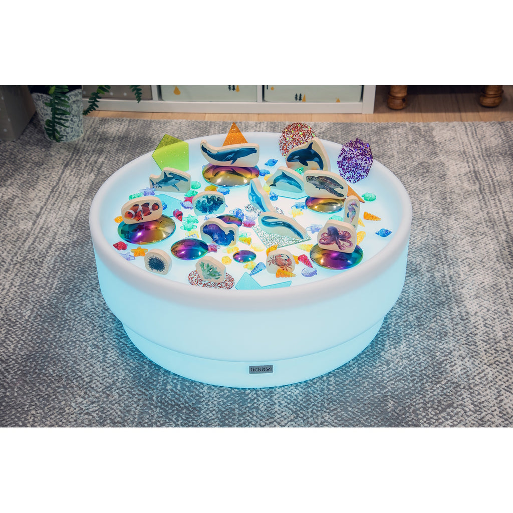 A softly glowing LED table with a shallow well, designed for sensory exploration, water play, and immersive learning experiences.