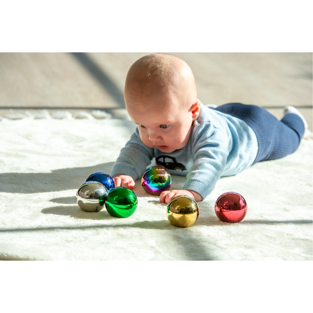 A set of colorful, reflective sensory balls that change appearance with movement, designed to engage children in tactile exploration and visual stimulation.