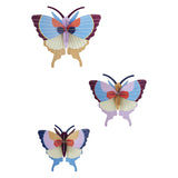 Three colorful, stylized butterfly wall decorations with layered wings in shades of blue, purple, and red, creating a whimsical and artistic tone.