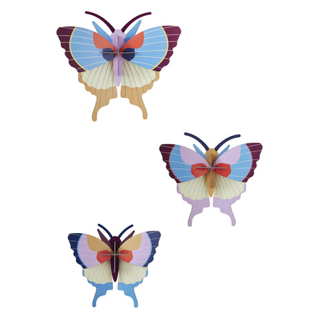 Three colorful, stylized butterfly wall decorations with layered wings in shades of blue, purple, and red, creating a whimsical and artistic tone.