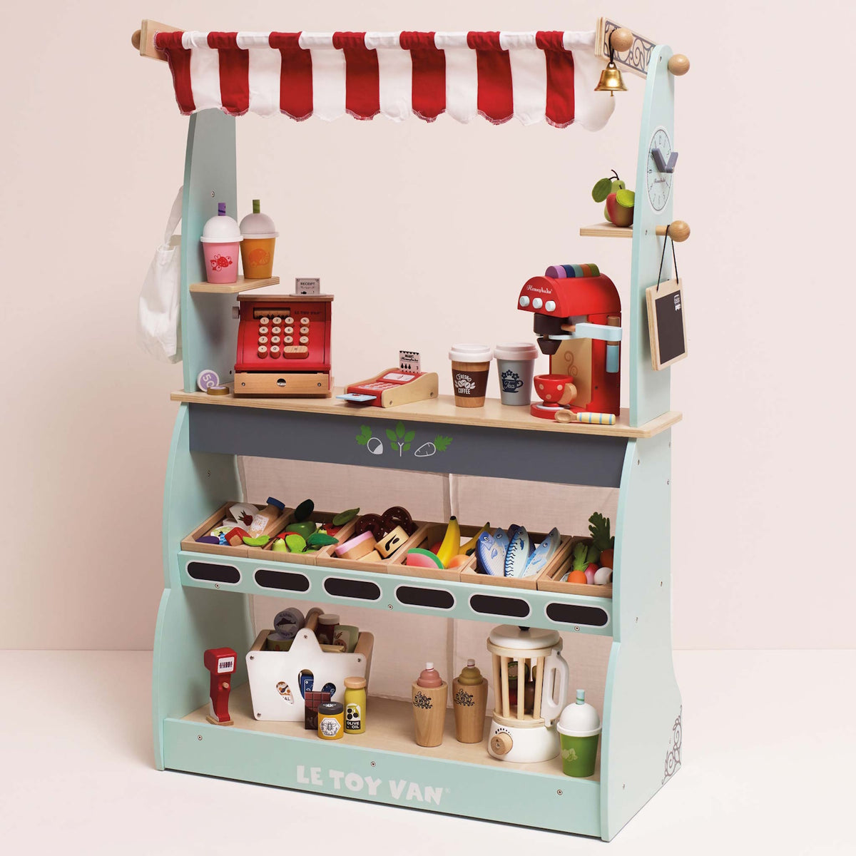 Wooden play market stall filled with toy groceries, cash register, and coffee maker on shelves.