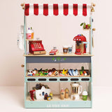 Wooden play market stall stocked with toy groceries, cash register, coffee maker, and play accessories.