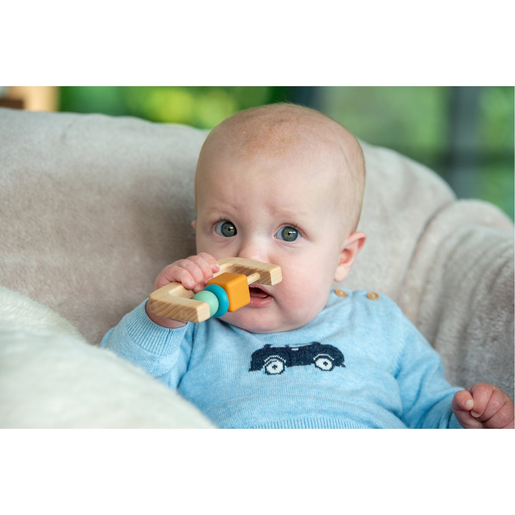 A soft silicone rattle with an arch design and soothing neutral colors, perfect for sensory play and developing motor skills in babies.