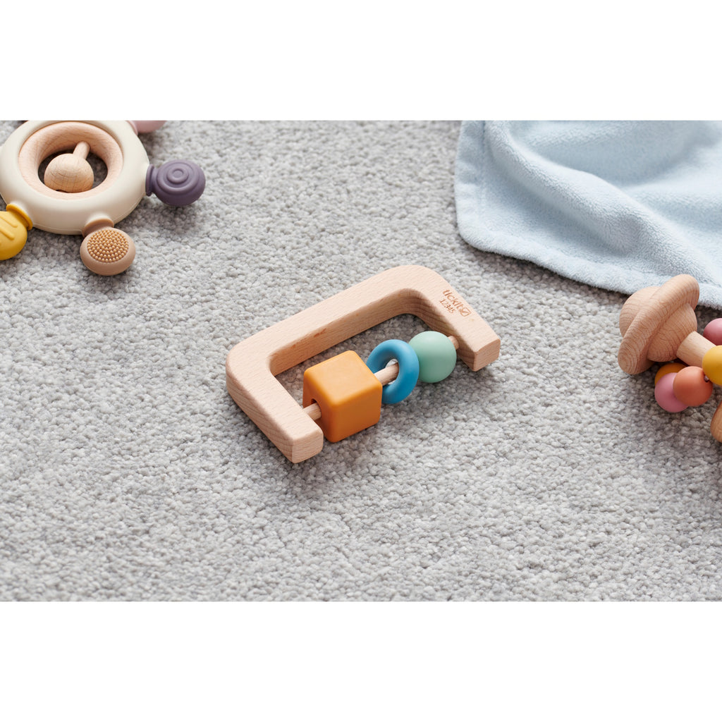 A soft silicone rattle with an arch design and soothing neutral colors, perfect for sensory play and developing motor skills in babies.