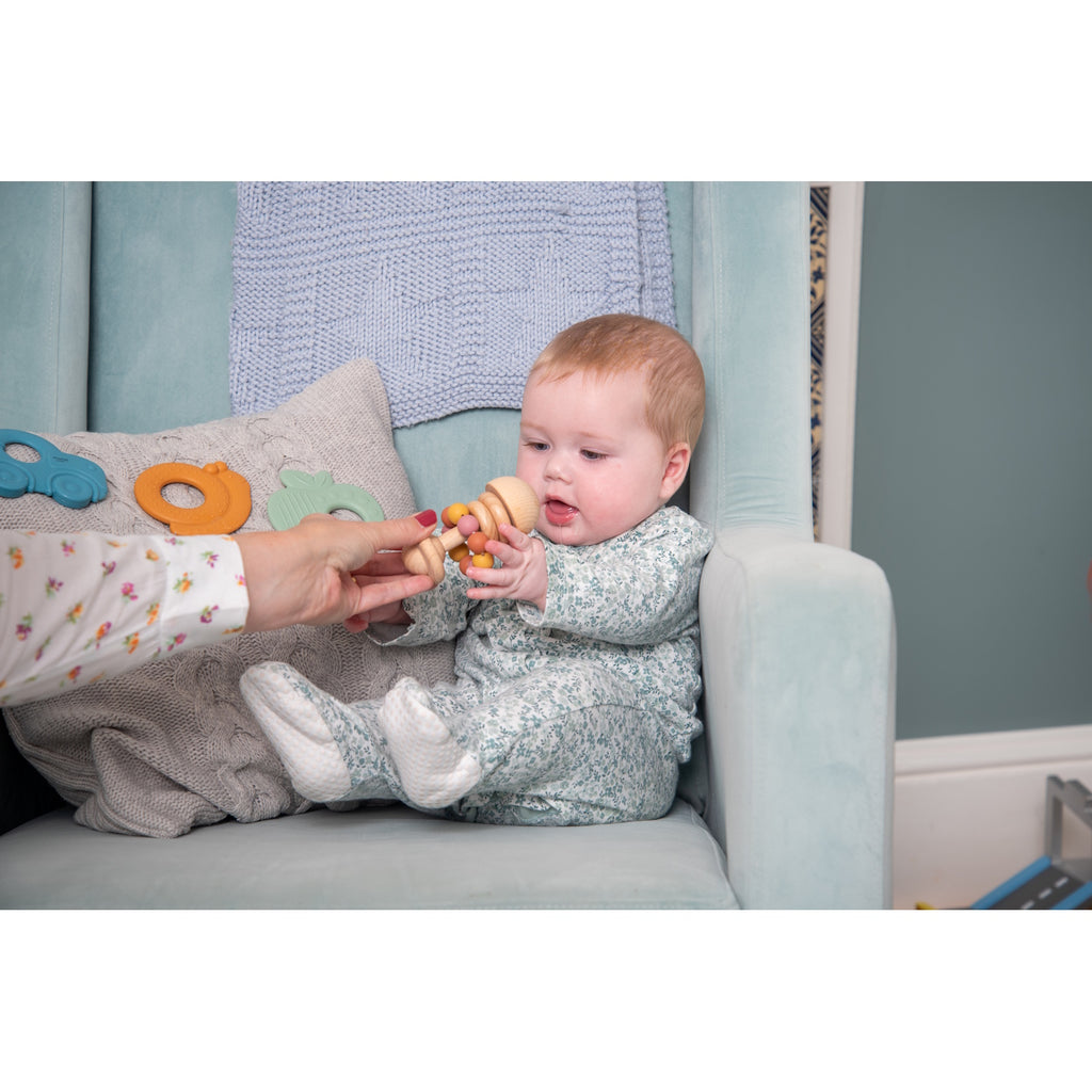 A soft silicone rattle featuring colorful beads in earthy tones, designed to stimulate sensory exploration and fine motor skills in babies.