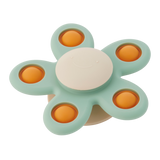 A soft silicone toy with a flower-shaped design, featuring gentle spinning motion in neutral colors, perfect for sensory play and motor skill development.