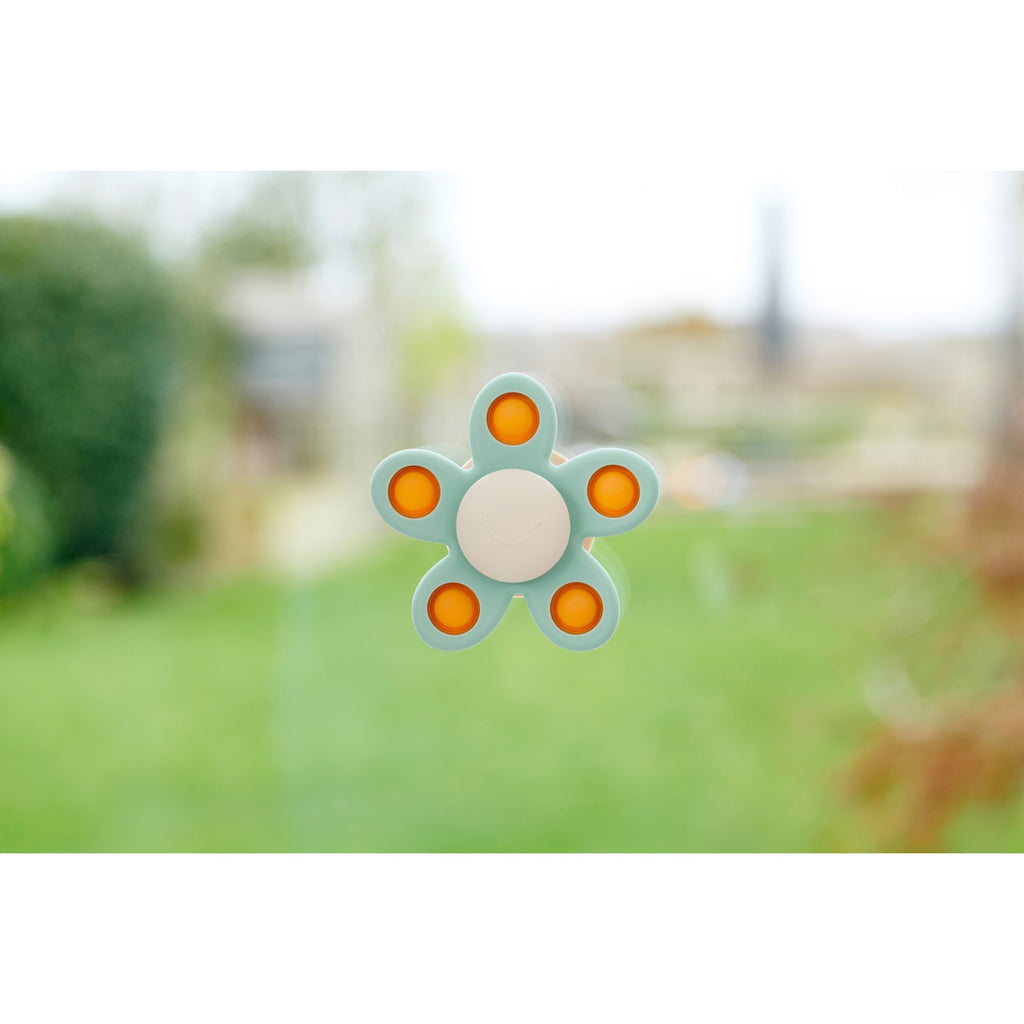 A soft silicone toy with a flower-shaped design, featuring gentle spinning motion in neutral colors, perfect for sensory play and motor skill development.