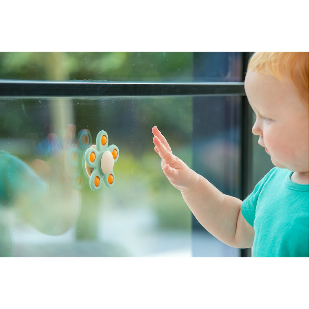 A soft silicone toy with a flower-shaped design, featuring gentle spinning motion in neutral colors, perfect for sensory play and motor skill development.