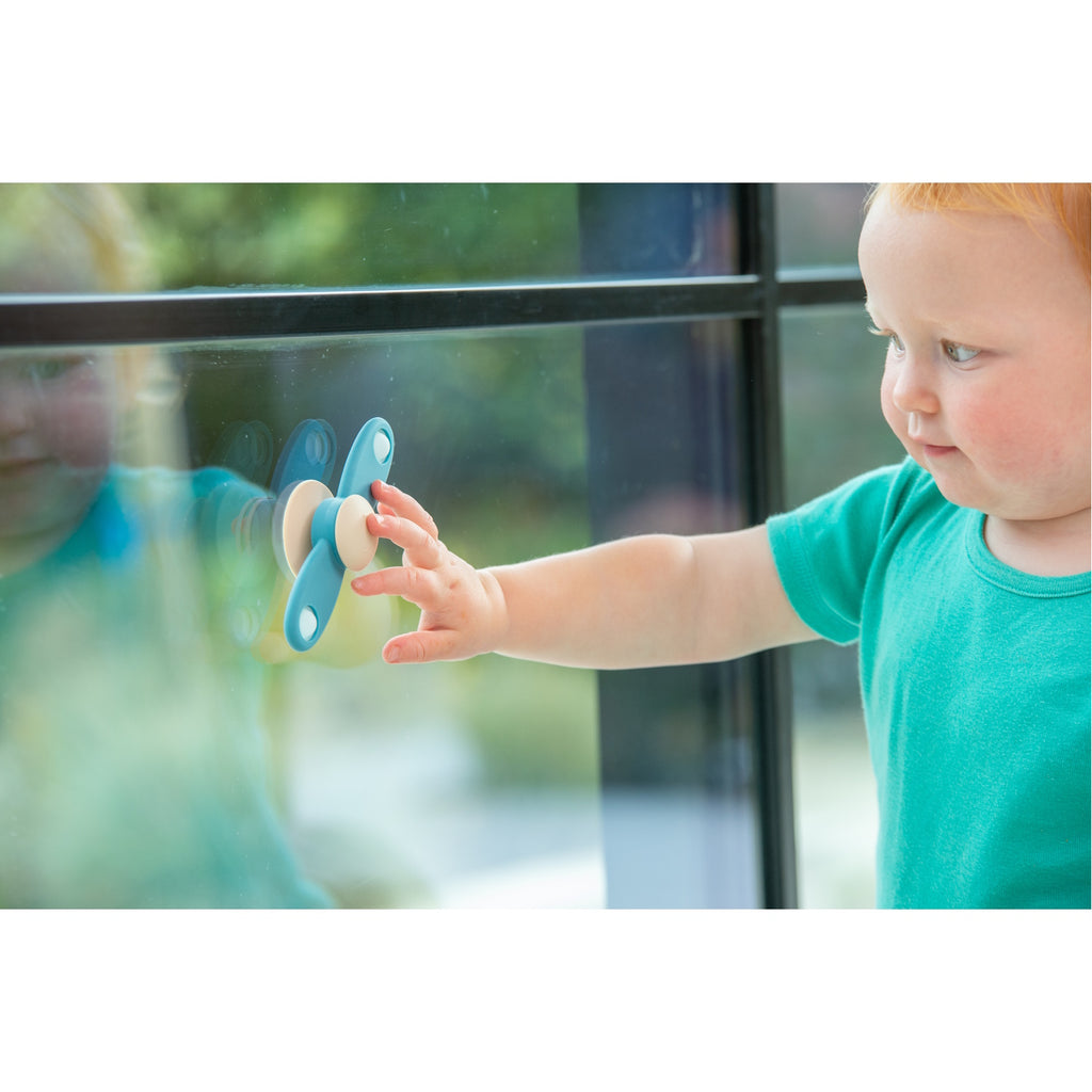 A soft silicone toy featuring a propeller design in neutral tones, ideal for sensory exploration and fine motor skill development.