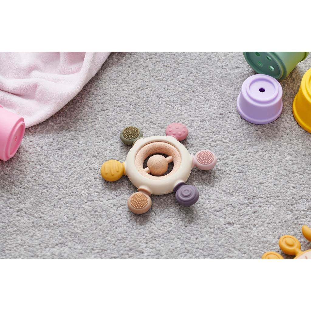 A soft silicone teether with a built-in rattle, designed in earthy tones to soothe and engage babies while promoting sensory development.