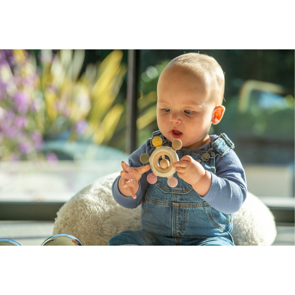 A soft silicone teether with a built-in rattle, designed in earthy tones to soothe and engage babies while promoting sensory development.