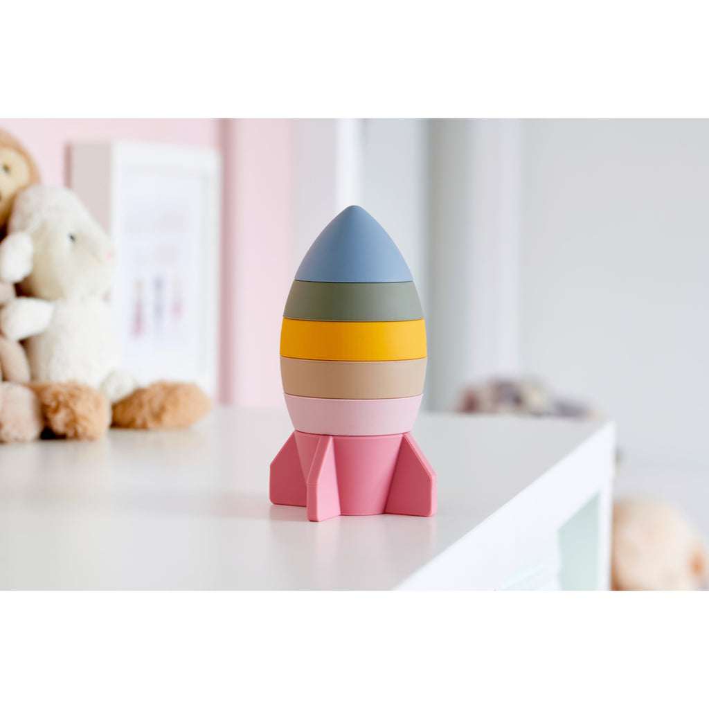A soft silicone stacking toy in earthy tones, shaped like a rocket, designed to encourage sensory exploration and fine motor skills.
