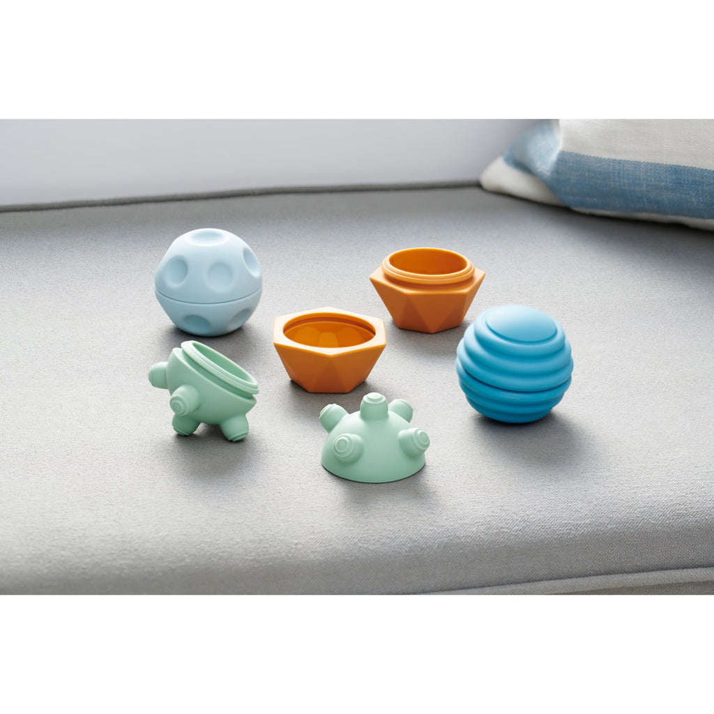 A set of soft silicone balls in neutral tones, featuring a textured surface to encourage tactile exploration and sensory development in young children.