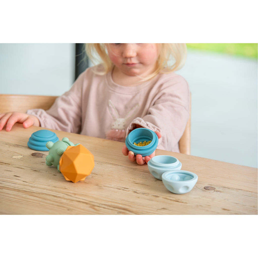 A set of soft silicone balls in neutral tones, featuring a textured surface to encourage tactile exploration and sensory development in young children.