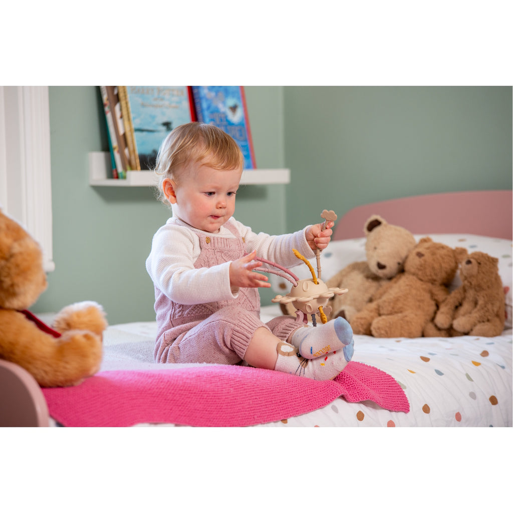 A soft silicone pull toy in earthy tones with textured zip-like ridges, designed to enhance sensory exploration and fine motor skills in young children.