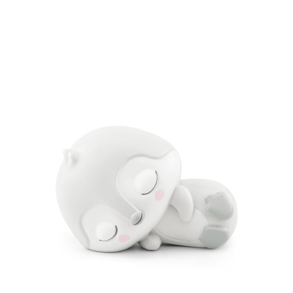 A cute, minimalist ceramic figurine of a sleeping penguin, predominantly white with gray accents and rosy cheeks in a white background.