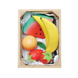 Top-down view of wooden play fruits packed in a crate lined with newspaper.