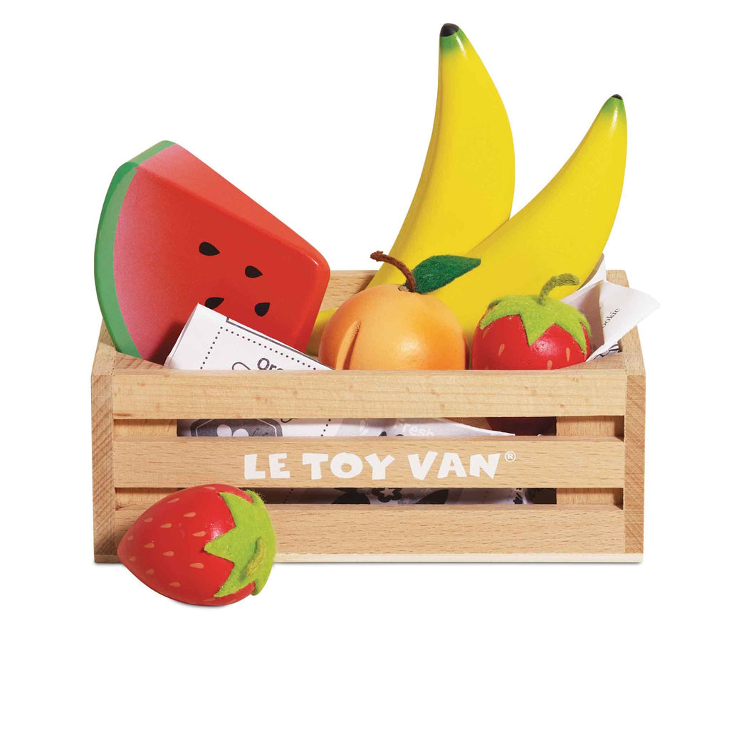 Wooden crate of colorful toy fruits, including bananas, strawberries, orange, and a watermelon slice. Bright, playful, and neatly arranged.