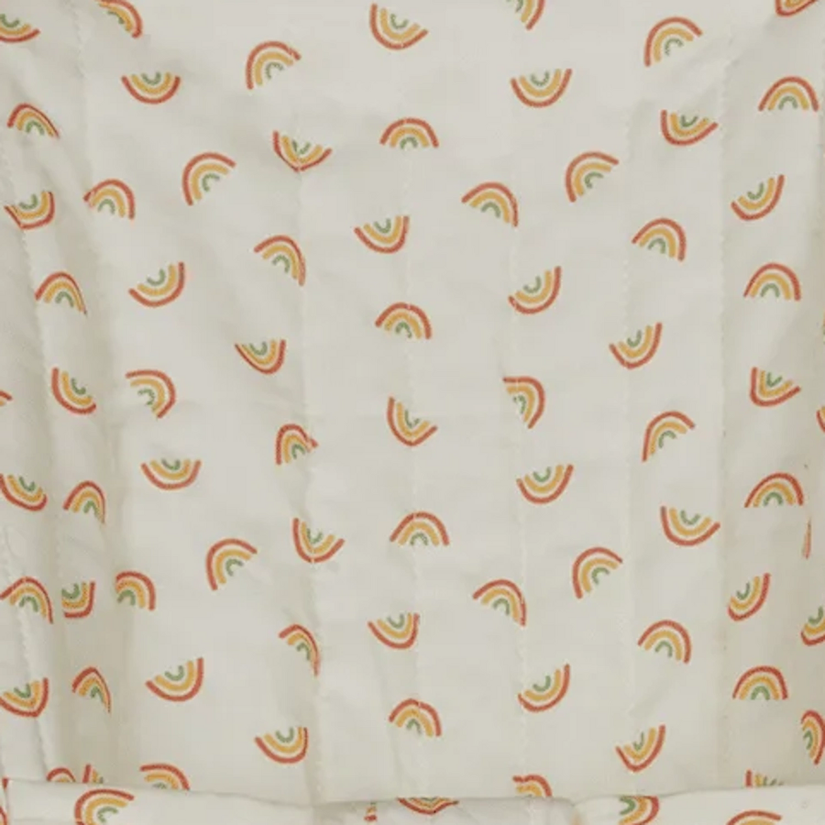 Close-up of off-white quilted fabric featuring a seamless pattern of colorful mini rainbows.