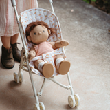 Cloth doll sitting in a toy stroller with a rainbow pattern seat lining.