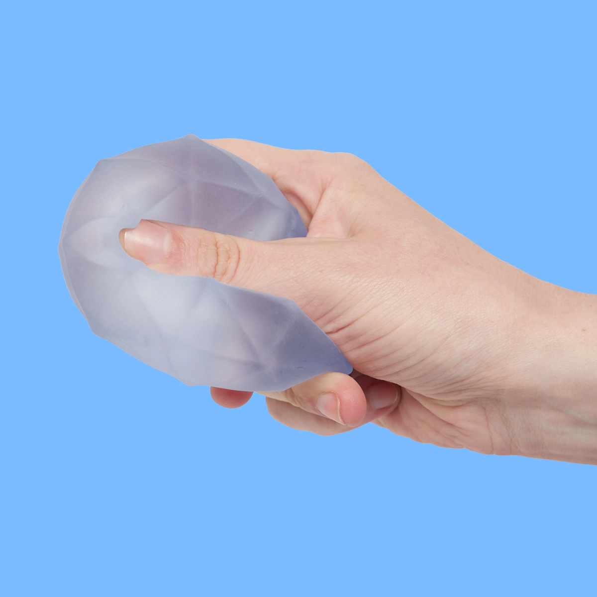 A hand squeezing a translucent, geometric-patterned stress ball against a light blue background, conveying a sense of calm and stress relief.
