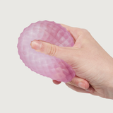 A hand squeezing a soft, textured, pink stress ball with a honeycomb pattern against a plain white background, conveying a sense of relief and relaxation.