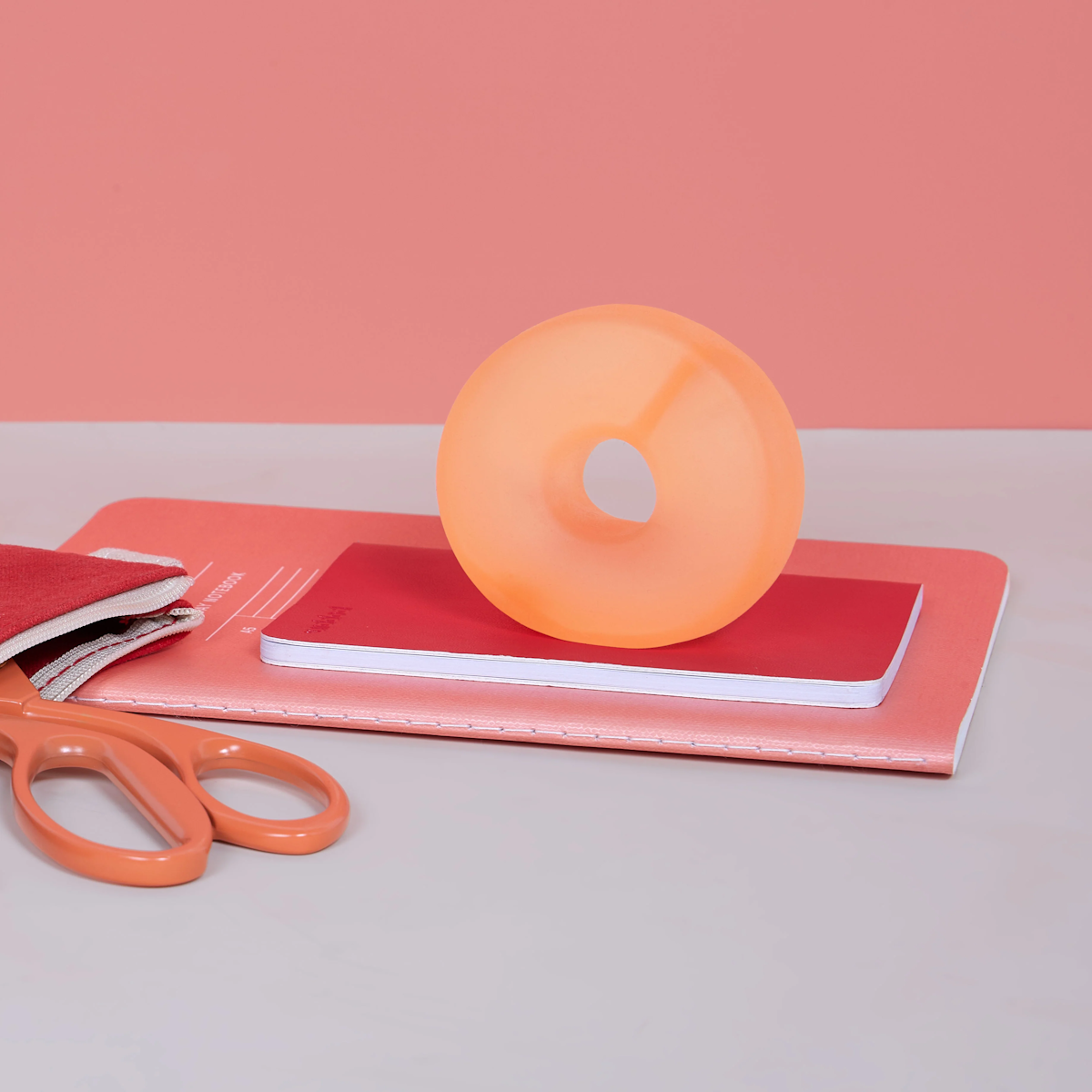 Orange Speks Loop Gump memory gel stress ring standing on notebook.