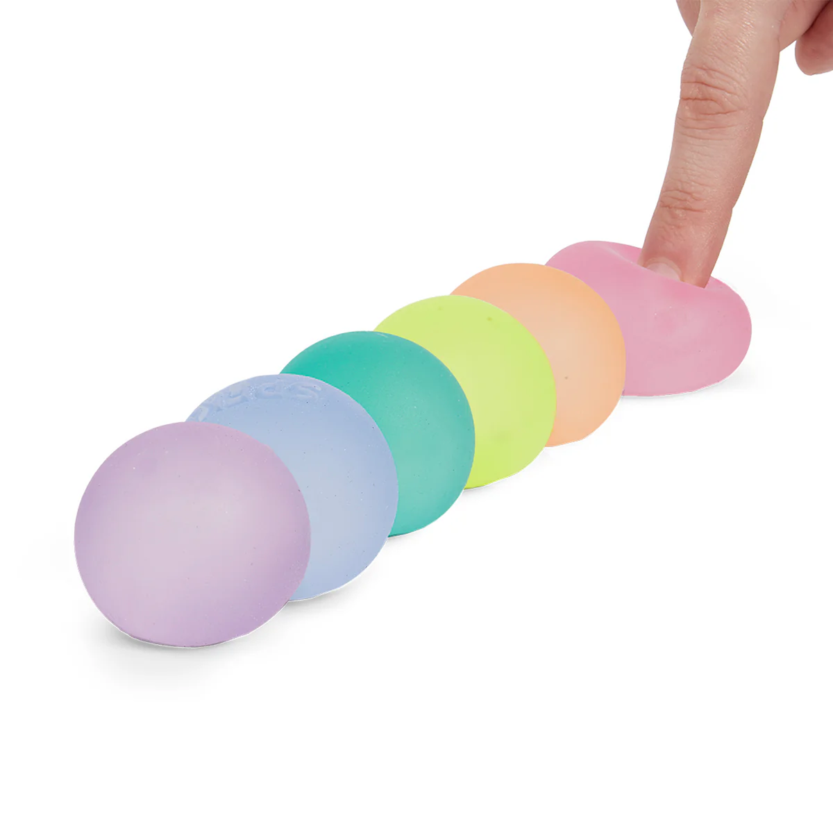 A row of six soft, pastel-colored stress balls in purple, blue, green, yellow, orange, and pink. A finger presses down on the pink ball, creating an indentation.