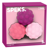 Three textured, round fidget desk magnets in purple, pink, and light pink are placed in a magenta box labeled "Speks Odds." The tone is playful.