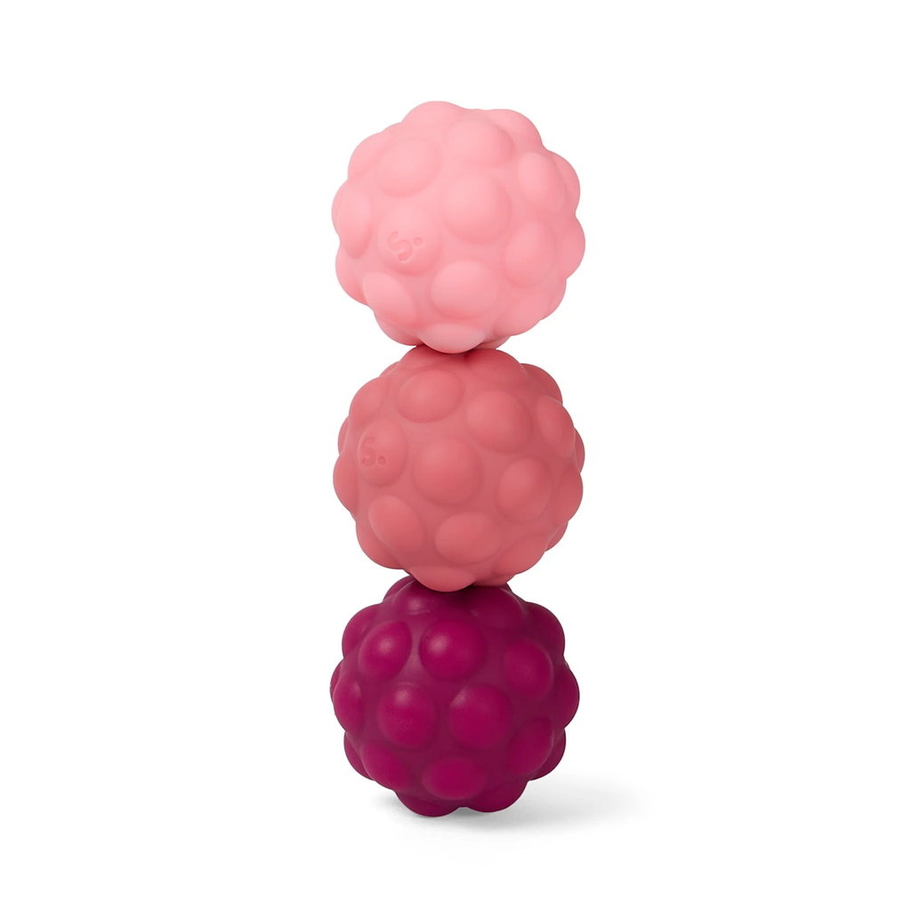 A stack of three textured balls in shades of pink and red, ranging from light to dark, placed vertically on a white background.