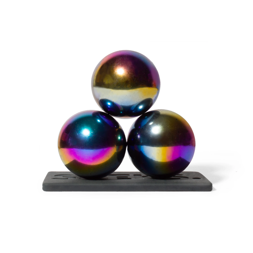 Three iridescent spheres with a rainbow-like sheen are stacked in a pyramid on a black base, reflecting light vibrantly against a white background.