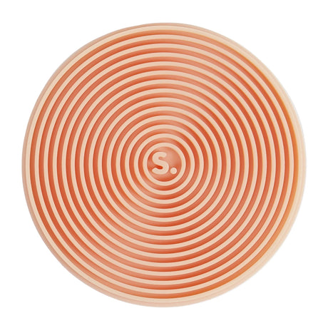 Circular orange silicone sensory sticker with concentric ridges and an "S." logo in the center.